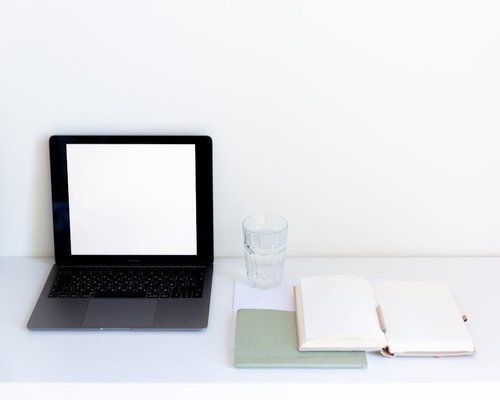 A modern shared workspace table with laptops, note books and a glass of clean water symbolizing office balance