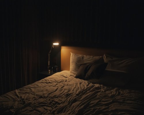 A quiet dark bedroom interior with a warm small lamp representing proper night sleep preparation